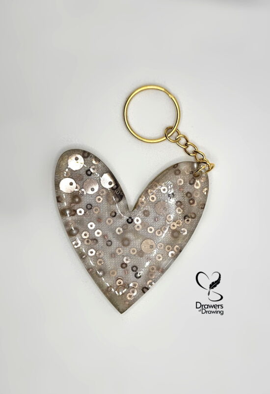 Ciondolo a cuore in resina trasparente con inclusione di tulle di seta, paillettes e perle con logo Drawers of Drawing