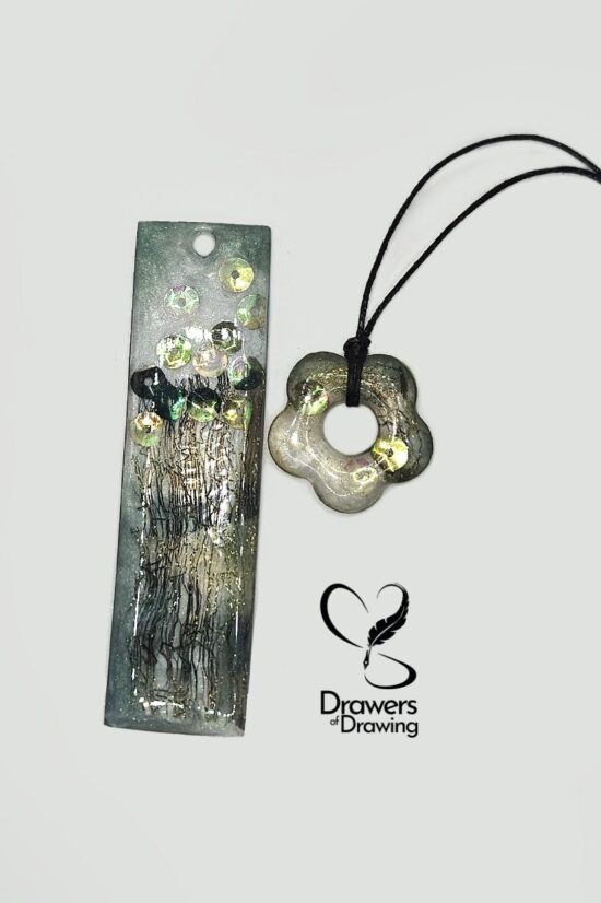 Set di portachiavi rettangolare e ciondolo a fiore in resina con inclusioni di tulle, paillettes e dettagli dorati su sfondo bianco con logo Drawers of Drawing